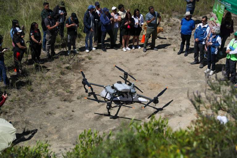 $!Personas observan al dron forestal Agras T20, de tecnología china, lanzando 20.000 semillas de especies nativas.