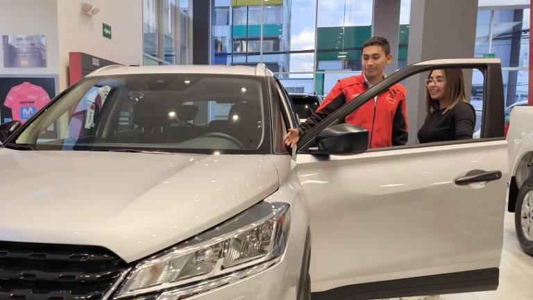 Jóven ecuatoriana examina las cualidades de su primer automóvil previo a la compra.