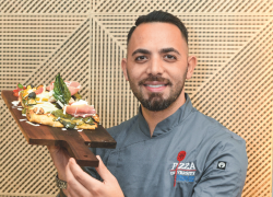 El chef Daniele Gagliotta posa en con una de sus elabradas pizzas, que proponen salirse de lo convencional.