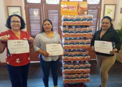 Tres tenderas recibieron certificados de becas por participar en el programa de capacitación.