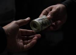 Fotografía referencial de una persona entregando dinero a otra.