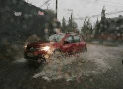 Fotografía referencial que muestra un auto atravesando un tramo inundado en la ciudad de Quito.