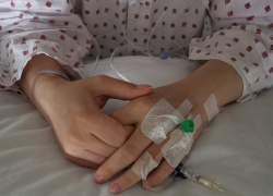 Fotografía de una menor de edad cruzando sus manos meintras yace en la cama de un hospital.