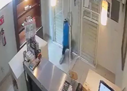Captura de video viralizado en la que aparece el sujeto intentando levantar la cortina de metal, después de que esta fuera cerrada por la empleada.