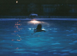 Fotografía referencial de una persona en una piscina de noche.