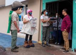 Fotografía cedida por el Parque Nacional Galápagos que muestra a miembros de la entidad mientras lanzan puerta a puerta una campaña para evitar el uso de bolsas plásticas, en Galápagos (Ecuador).