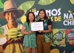 Una de las mujeres que se dedica al pelado del plátano recibe un certificado por la capacitación recibida en el marco del programa “Las Manos Detrás de Natuchips®”.