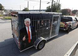 Un partidario del expresidente estadounidense Donald Trump remolca una celda improvisada que contiene representaciones de líderes demócratas, frente a la entrada de la cárcel del condado de Fulton.