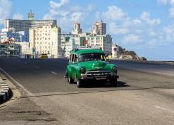 Un automóvil estadounidense antiguo circula por una tranquila avenida en La Habana.