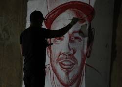 El artista Julián Castillo pinta un retrato del cantante puertorriqueño Residente con sangre humana en el barrio Siloé, en Cali (Colombia).