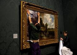 Activistas del grupo de campaña 'Just Stop Oil' cubren la pintura 'The Hay Wain' del artista inglés John Constable, en una versión simulada 'sin fecha' que incluye carreteras y aviones, antes de pegar sus manos al marco en protesta contra el uso de combustibles fósiles, en la National Gallery de Londres.