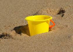 Fotografía referencial de un balde sobre arena.