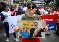 Una protestante alineada al gobierno de Nicolás Maduro, sosteniendo una foto de él junto a Cilia Flores.