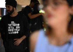 Un estudiante venezolano con una camiseta que dice El futuro está en nuestras manos sale luego de asistir a la presentación en vivo de su podcast A Medias en el auditorio de la Universidad del Zulia en Maracaibo.
