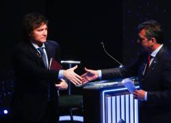 Fotografía de Javier Milei (I) y Sergio Massa (D) a punto de estrechar manos tras encararse en un debate.