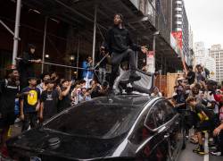 Una persona se sube a un automóvil durante los disturbios provocados por el transmisor de Twitch Kai Cenat, quien anunció un evento de regalo, en Union Square de Nueva York el 4 de agosto de 2023.