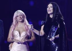 La cantante italiana Laura Pausini sostiene su Grammy Persona del Año junto a la colombiana Karol G (i) en la gala anual de los Latin Grammy.