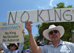 Personas se manifiestan sosteniendo carteles durante la protesta 'No Kings', este sábado, en Miami, Estados Unidos.