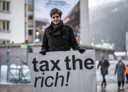 La austriaca Marlene Engelhorn, que heredó de su familia la propiedad del gigante químico alemán BASF, posa con un cartel que dice ¡Cobren impuestos a los ricos!, en la entrada del centro de congresos en la inauguración de la reunión anual del Foro Económico Mundial (FEM) en Davos, el 15 de enero de 2024.