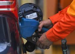 Un empleado de una gasolinera suministra combustible a un vehículo.