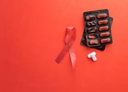 Una cinta roja en representación del VIH y pastillas médicas.
