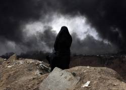 Una mujer iraní con velo, miembro de la Media Luna Roja de Irán, observa mientras el humo aún se eleva desde la refinería de petróleo de Shahran tras el ataque aéreo de anoche en Teherán.