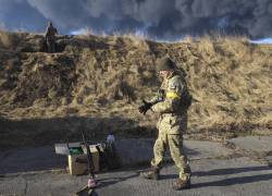 Los militares ucranianos descansan en una posición mirando el humo de un depósito de almacenamiento de petróleo quemado después de que un misil ruso atacara cerca de Kiev, Ucrania.