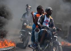 Hombres en motocicletas pasan quemando neumáticos durante una manifestación tras la dimisión de su primer ministro Ariel Henry, en Puerto Príncipe, Haití, el 12 de marzo de 2024.