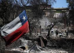 Una bandera chilena ondea mientras los vecinos limpian sus tierras y queman casas en Villa Independencia, región de Valparaíso, Chile, el 5 de febrero de 2024.