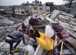 La gente rescata algunos artículos entre los escombros de la casa de la familia palestina al-Atrash, después de que fuera destruida en un ataque israelí en Deir el-Balah.