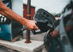 Fotografía referencial de una persona poniéndole combustible a su auto.