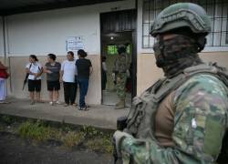 Personal militar hace guardia mientras las mujeres hacen cola para votar en un colegio electoral en Canuto, en la provincia de Manabí, el 9 de febrero de 2025.