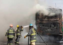 Integrantes del Cuerpo de Bomberos de Guadalajara intentan apagar un vehículo incendiado este domingo.