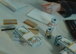 Billetes de dólares y tarjetas bancarias sobre un escritorio, en una representación de operaciones financieras y manejo de crédito.