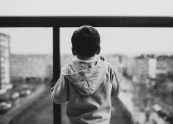 Imagen de referencia de un niño viendo una urbe a través de un vidrio.