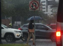 Fotografía de una ciudadana cubriéndose de una fuerte lluvia en Quito.