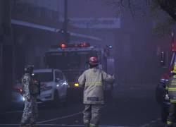 Fotografía que muestra a bomberos combatiendo un incendio originado en un edificio en el que había una amplia bodega con mercaderia, en el centro de Guayaquil.