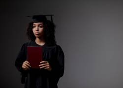 Imagen de referencia de una joven sosteniendo lo que sería su diploma de graduación.