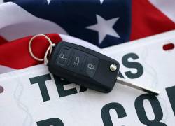 Llave de vehículo sobre placa vehicular de Texas y bandera de Estados Unidos.