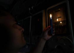 Un ciudadano ecuatoriano revisa un medidor de luz con una vela durante un apagón.