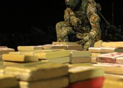 Fotografía que muestra a un uniformado apilando paquetes de cocaína.