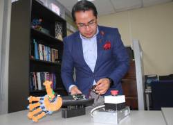 Marco Benalcázar, director del laboratorio de Investigación en IA de la Escuela Politécnica Nacional prueba una prótesis de mano.