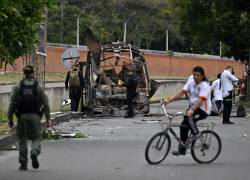 Agentes colombianos de desactivación de explosivos inspeccionan un autobús calcinado tras la explosión de una bomba cerca de una base militar en Cali, departamento del Valle del Cauca, Colombia.
