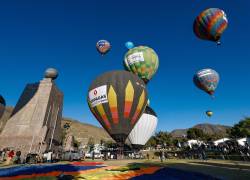 Personas observan globos aerostáticos durante la V edición del Festival de Globos este viernes, en la ciudad Mitad del Mundo, en el noroeste de Quito.