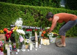 Una mujer deposita flores en un memorial improvisado en honor a un hombre que murió tras recibir disparos de agentes del Servicio de Inmigración y Control de Aduanas de EE. UU. (ICE).