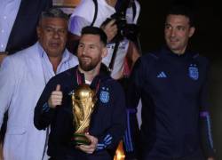 Lionel Messi (c) de la selección argentina de fútbol saluda con el trofeo del Mundial de Fútbol Catar 2022 junto al seleccionador Lionel Scaloni (d) a su llegada hoy, al Aeropuerto Internacional de Ezeiza.