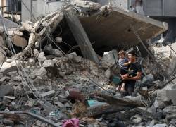 Un joven palestino sostiene a su hermano menor mientras se encuentra entre los escombros de un edificio destruido en Rafah, en el sur de la Franja de Gaza, el 13 de noviembre de 2023, en medio de las batallas en curso entre Israel y el grupo militante palestino Hamás.