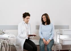 Mujer embarazada en consulta ginecológica revisando exámenes.