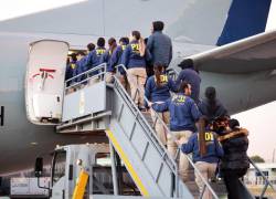 Oficiales escoltando a un grupo de migrantes que abordan una aeronave de la Fuerza Aérea de Chile mientras son deportados desde el aeropuerto Arturo Merino Benítez, en Santiago, el 16 de abril de 2026.