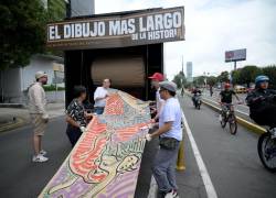 Voluntarios desenrollan una obra del artista ecuatoriano Franz del Castillo en la calle del norte de Quito, el 6 de abril de 2025.